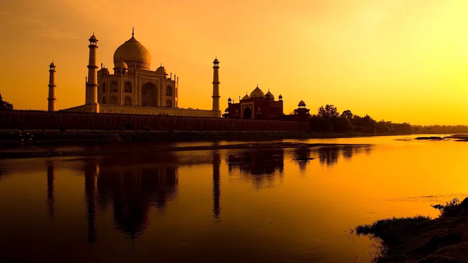 Taj Mahal silhouetted against an orange sunset over the Yamuna
